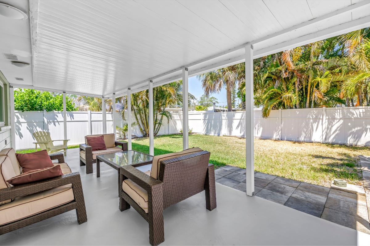 Covered lanai opening to a fenced yard with palms