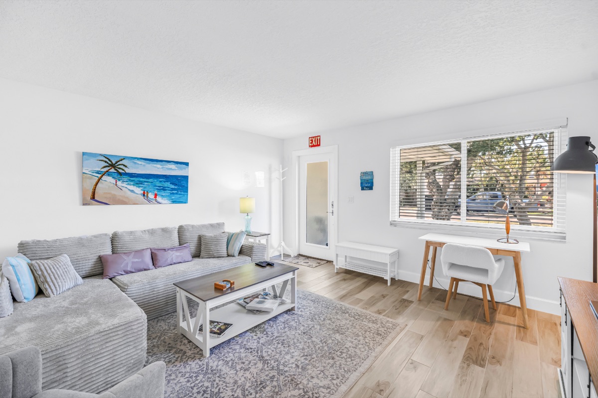 Living room with a framed beach scene and warm wood floors